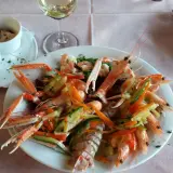 Un piatto di scampi e gamberi con verdure miste, un bicchiere di vino bianco e salse, un'ottima cena al conte Max Monte Roberto.