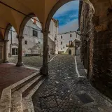 Arco medievale con vista su vicolo lastricato e case antiche. Un assaggio di cosa vedere a Narni, tra storia e fascino.