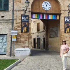 Una donna sorride sotto l'arco di Porta San Martino a Castelfidardo, un luogo ricco di storia e musica da scoprire.
