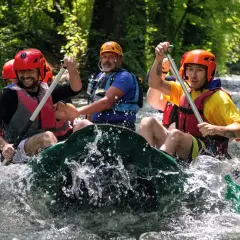Un gruppo di amici si diverte in un'avventura di rafting nelle Marche, pagaiando con entusiasmo tra le rapide.