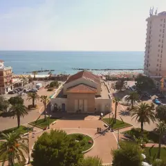Piazza centrale con teatro, palazzi, palme e mare sullo sfondo. Ecco cosa vedere a Porto Recanati.
