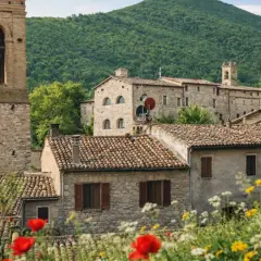 Esanatoglia cosa vedere: borgo medievale con torre campanaria, case in pietra e fiori colorati.
