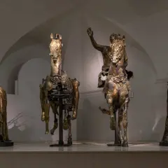 Statue equestri e figure umane in bronzo dorato, un'antica **pergola** che evoca le Marche.