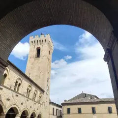 Arco in mattoni incornicia la torre civica e il palazzo comunale di Montelupone, un luogo da scoprire.