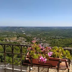 Vista panoramica su un borgo tra colline verdi. Un balcone fiorito offre un'ottima prospettiva su cosa vedere a Pretoro.