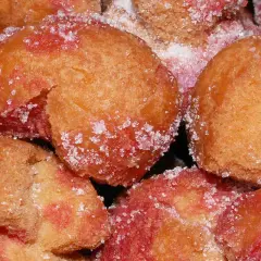 Scroccafusi di Macerata, dolcetti dorati e rosati, cosparsi di zucchero cristallino, pronti per essere gustati.