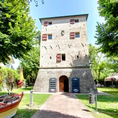 Torre dell'orologio nel centro storico di Igea Marina, con barche e bandiere colorate.