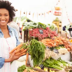 Donna sorridente al mercato con carote fresche, un vero km zero menù.