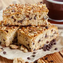 Fette di ciambellone marchigiano ricetta originale, con gocce di cioccolato e noci, accanto a una tazza di caffè.
