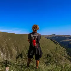 Persona con zaino ammira il panorama durante un trekking di 3 giorni nei Monti Sibillini.