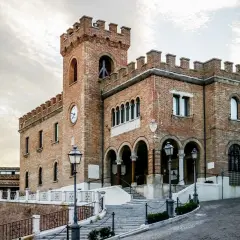 Edificio storico in mattoni a Mondolfo, cosa vedere: torre con orologio, archi e scalinata.