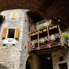 Un vicolo suggestivo nel canale di Tenno, con balconi fioriti e scorci antichi da scoprire.