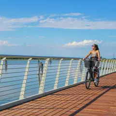 Due donne in bicicletta su una moderna pista ciclabile jesi, con il mare e il cielo azzurro sullo sfondo.