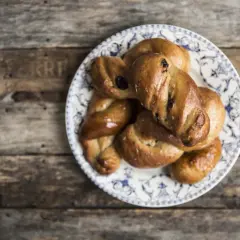 Piatto di biscotti di mosto marchigiani, intrecciati e dorati, su un tavolo di legno rustico.