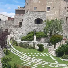 Un angolo suggestivo del centro storico di Rieti, con antiche mura in pietra, un giardino curato e una statua.