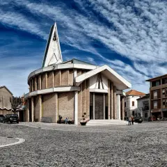 Piazza del centro di Numana con una chiesa moderna, cielo blu e nuvole bianche.