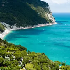 Spiaggia affollata e mare turchese, un campeggio immerso nel verde. Perfetto per scoprire le località balneari Marche economiche.