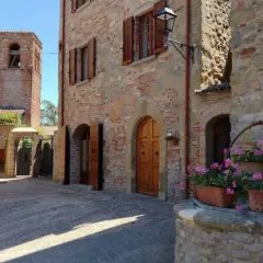 Un vicolo in pietra con un pozzo fiorito e un campanile sullo sfondo. Citerna cosa vedere: un borgo medievale incantevole.
