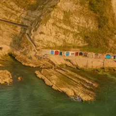 Piccole casette colorate a ridosso della scogliera, con il mare verde smeraldo che lambisce le rocce. Un angolo di paradiso vicino alla grotta azzurra di Ancona.