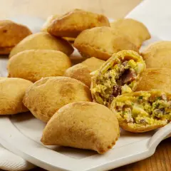Calcioni di ricotta abruzzesi dorati e fragranti, uno aperto rivela un ripieno saporito.