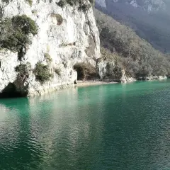 Acqualagna cosa vedere: un lago smeraldo incastonato tra imponenti pareti rocciose con grotte naturali.