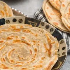 Crescia marchigiana dorata e sfogliata, servita su un piatto decorato. Un sapore autentico delle Marche.