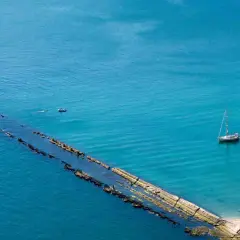 La spiaggia del Trave, con le sue acque cristalline, ospita due barche a vela e un piccolo motoscafo.