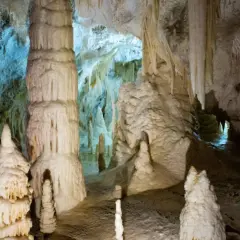 Stalattiti e stalagmiti imponenti nelle Grotte di Genga, Marche, creano un paesaggio sotterraneo surreale.