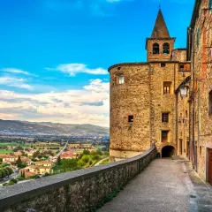 Un vicolo storico con un torrione medievale e una vista panoramica sulla valle. Perfetto per scoprire le cose da fare a Anghiari.