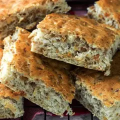 Fette di pizza con i grasselli, dorate e fragranti, con un impasto rustico e alveolato.