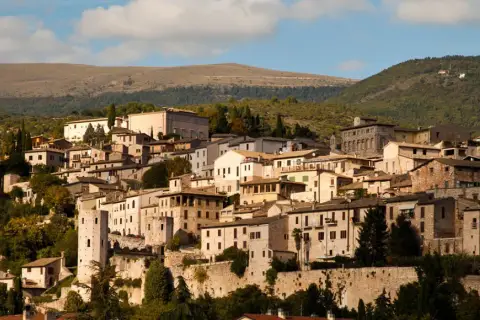 Spello, un borgo umbro incastonato tra colline verdi, con case in pietra e torri antiche che si stagliano contro il cielo azzurro.