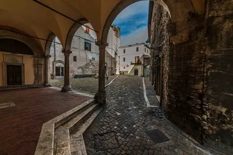 Arco medievale con vista su vicolo lastricato e case antiche. Un assaggio di cosa vedere a Narni, tra storia e fascino.