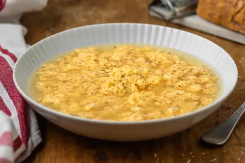 Stracciatella in brodo marchigiana, un piatto confortante con uova strapazzate in brodo, pepe nero e un tocco di formaggio grattugiato.