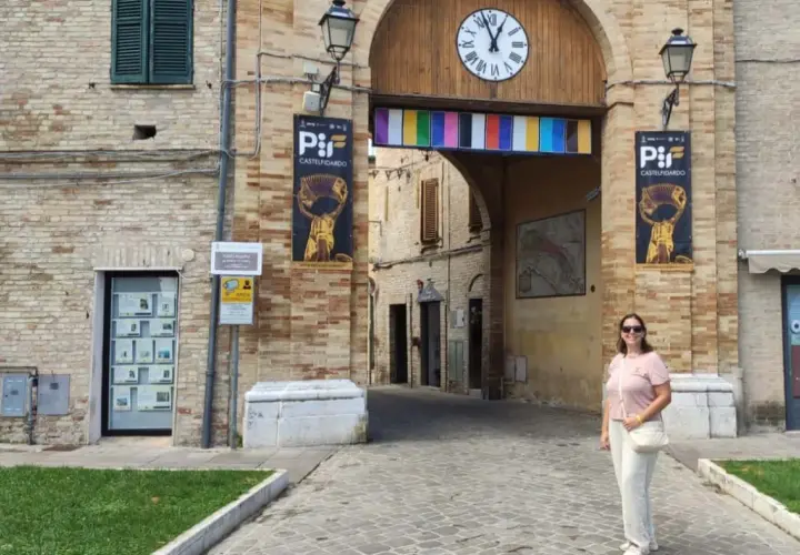 Una donna sorride sotto l'arco di Porta San Martino a Castelfidardo, un luogo ricco di storia e musica da scoprire.