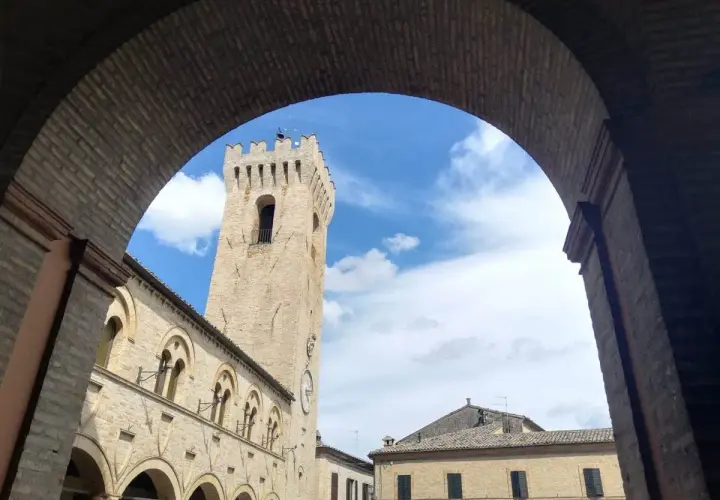 Arco in mattoni incornicia la torre civica e il palazzo comunale di Montelupone, un luogo da scoprire.