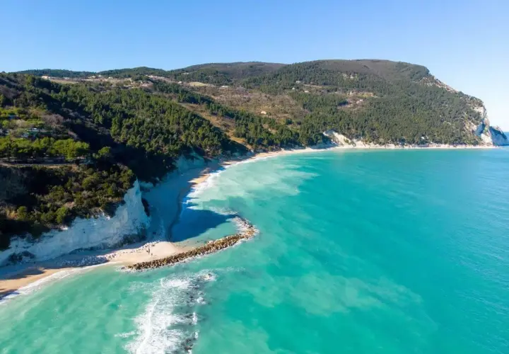 Vista aerea della spiaggia di Numana Alta, con le sue scogliere bianche, la pineta e il mare cristallino.