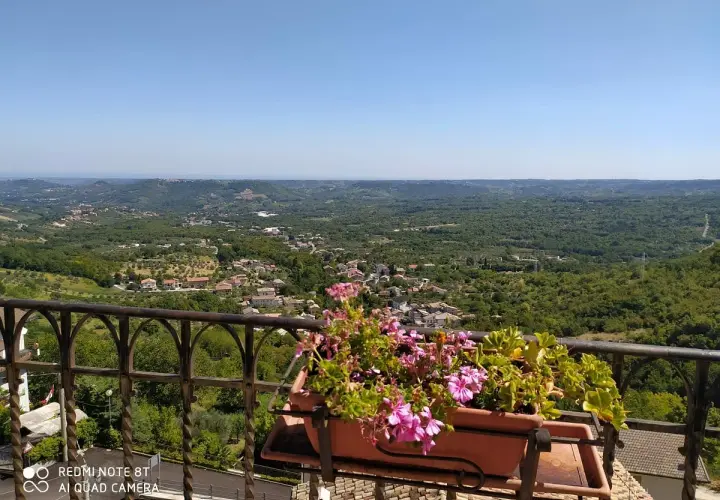 Vista panoramica su un borgo tra colline verdi. Un balcone fiorito offre un'ottima prospettiva su cosa vedere a Pretoro.