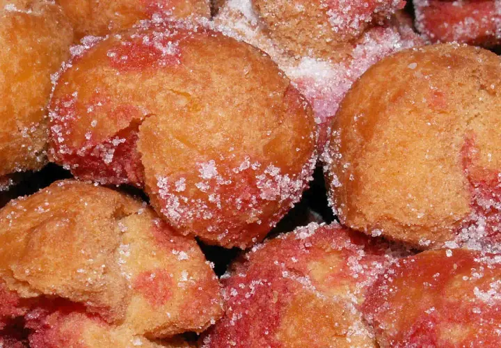 Scroccafusi di Macerata, dolcetti dorati e rosati, cosparsi di zucchero cristallino, pronti per essere gustati.