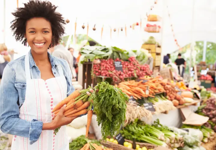 Donna sorridente al mercato con carote fresche, un vero km zero menù.