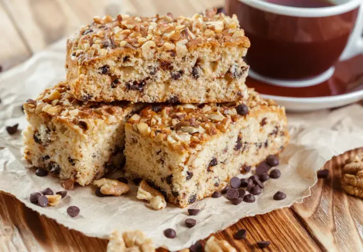 Fette di ciambellone marchigiano ricetta originale, con gocce di cioccolato e noci, accanto a una tazza di caffè.