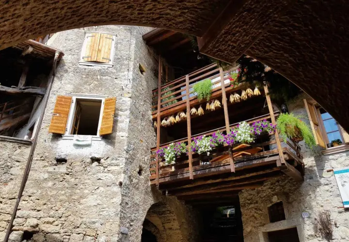 Un vicolo suggestivo nel canale di Tenno, con balconi fioriti e scorci antichi da scoprire.