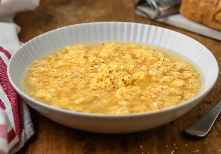 Stracciatella in brodo marchigiana, un piatto confortante con uova strapazzate in brodo, pepe nero e un tocco di formaggio grattugiato.