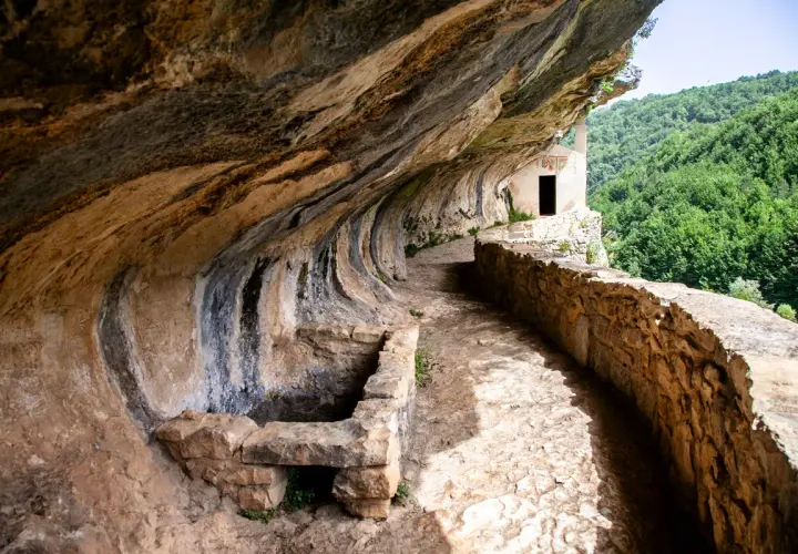 Sentiero roccioso verso l'eremo di San Bartolomeo, incastonato nella roccia con vista su boschi rigogliosi. Come arrivare?