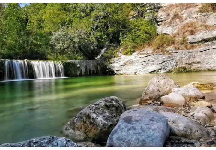 Le cascatelle di Castel Trosino creano un'oasi verde smeraldo, con rocce levigate e vegetazione lussureggiante.