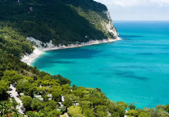 Spiaggia affollata e mare turchese, un campeggio immerso nel verde. Perfetto per scoprire le località balneari Marche economiche.