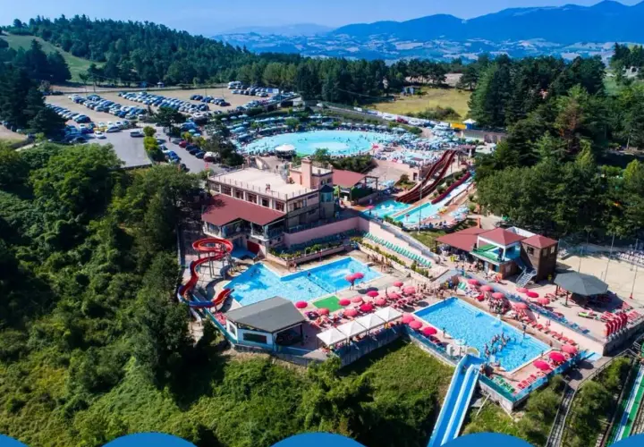 Vasta area con piscine, scivoli e ombrelloni rossi, immersa nel verde delle colline. Un divertente parco acquatico nelle Marche per tutta la famiglia.
