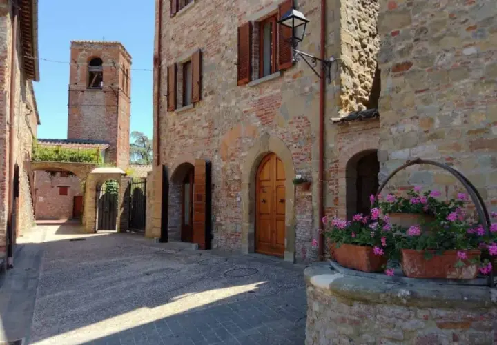 Un vicolo in pietra con un pozzo fiorito e un campanile sullo sfondo. Citerna cosa vedere: un borgo medievale incantevole.