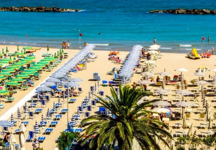 San Benedetto del Tronto: un'ampia spiaggia dorata con file ordinate di ombrelloni verdi e bianchi, lettini e palme. Il mare pulito invita al relax.