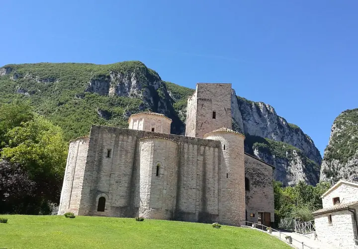 Genga, cosa vedere: l'antica Abbazia di San Vittore, un gioiello romanico incastonato tra montagne verdi e un cielo azzurro.