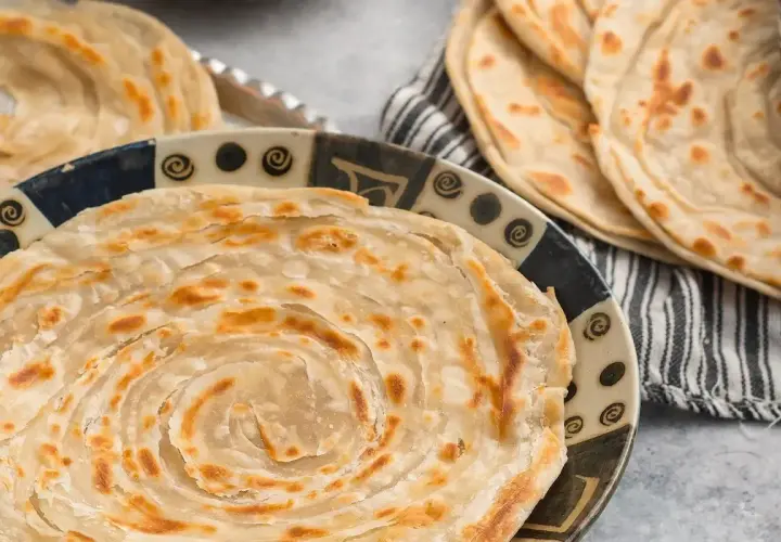 Crescia marchigiana dorata e sfogliata, servita su un piatto decorato. Un sapore autentico delle Marche.